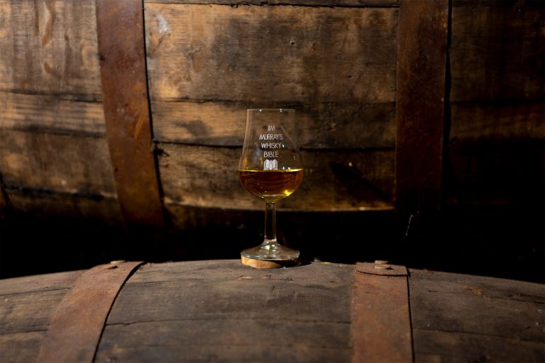 A single whisky glass on a barrel